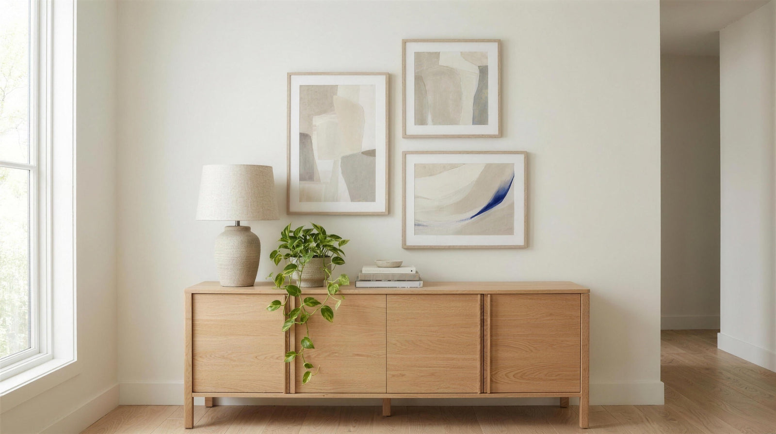 Oak sideboard with a ceramic table lamp and three framed art prints